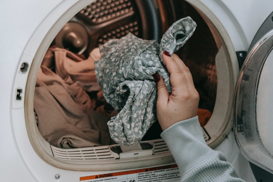 ドラム式洗濯機に洗濯物を入れる女性の手